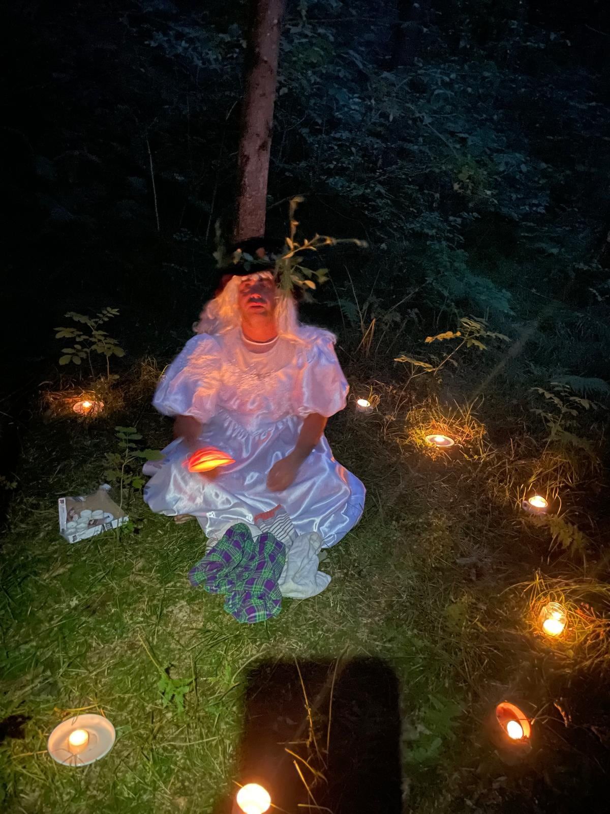 Eine verkleidete Waldfee sitzt am Abend zwischen kleinen Lichtern